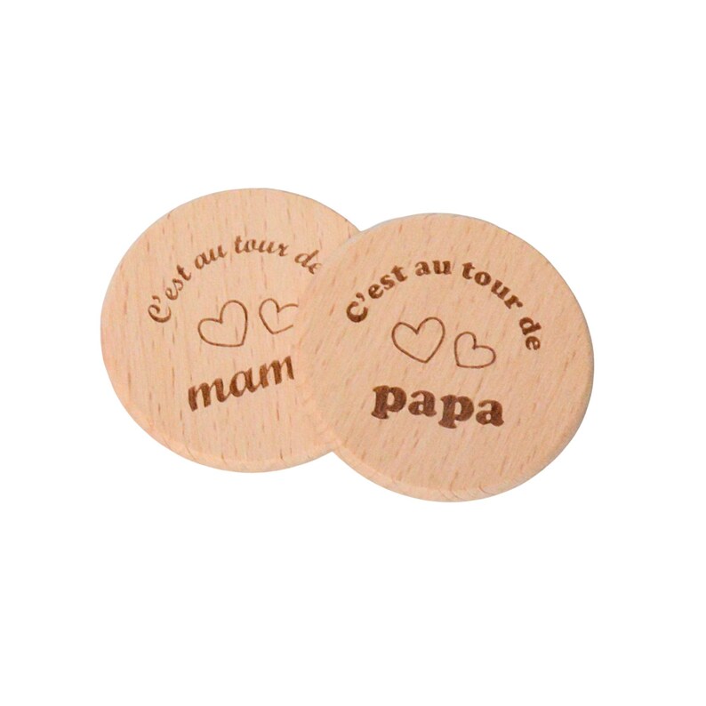 May include: Two round wooden coasters with the text "C'est au tour de" and two hearts above the words "mam" and "papa".