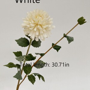 May include: A single white artificial dahlia flower stem with green leaves. The stem is 30.71 inches long.  The flower is a cream color and has a layered, ruffled appearance.  The stem has a bud at the top.