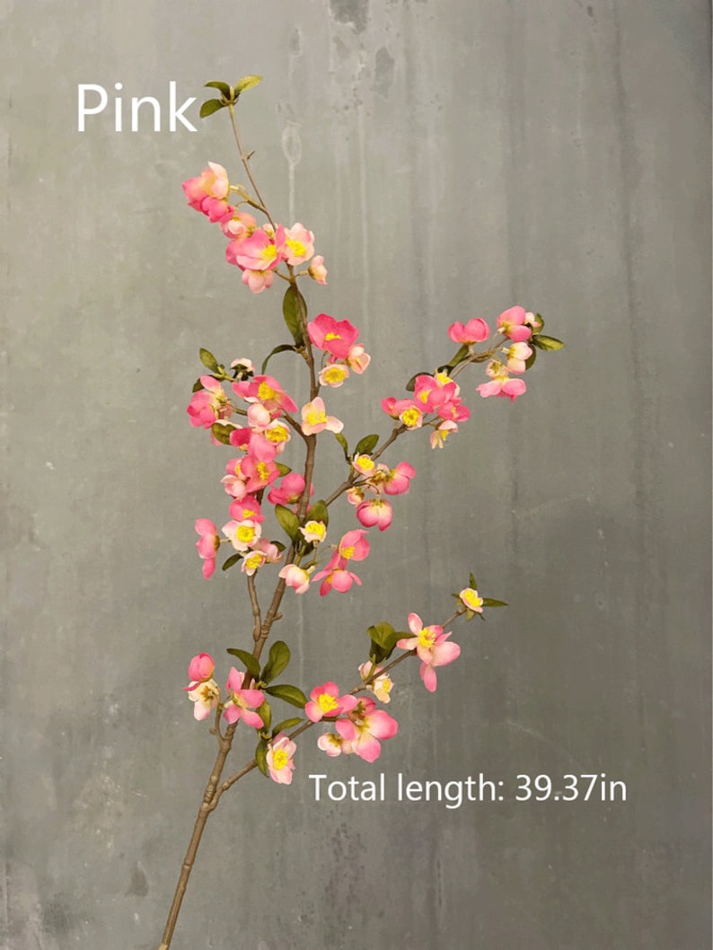 May include: A pink artificial flower branch with small pink flowers and yellow centers. The branch is 39.37 inches long.  The branch is against a gray background.