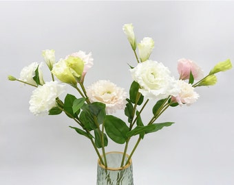 May include: A bouquet of artificial flowers in shades of white, pink, and green. The flowers are arranged in a vase with a textured surface.