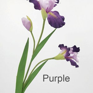 May include: Purple artificial iris flower stem with three blooms, one open and two buds. The stem has long green leaves.