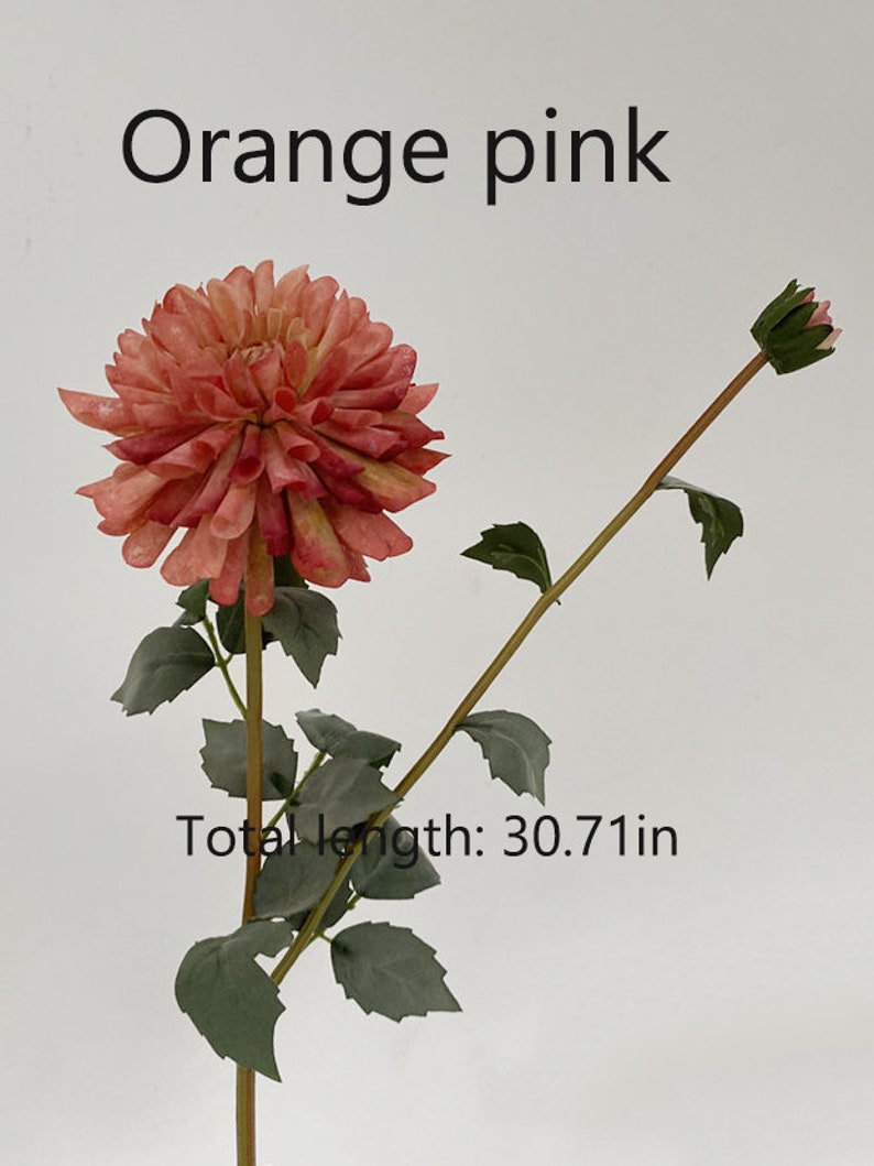 May include: A single stem artificial flower with a large orange-pink dahlia bloom and a smaller bud. The stem is green with leaves and measures 30.71 inches in length.  "Orange pink" is written above the flower.
