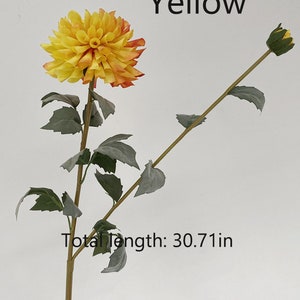 May include: A single artificial yellow and orange dahlia flower stem with green leaves. The stem is 30.71 inches long. The text "Yellow" is written above the flower and the text "Total Length: 30.71 in" is written below the flower.