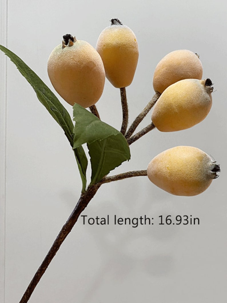 May include: A branch with five yellow felt fruit and green leaves. The branch is brown and has a total length of 16.93 inches.