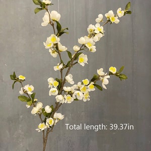 May include: White artificial flower branch with small white blossoms and green leaves. The branch is 39.37 inches long.