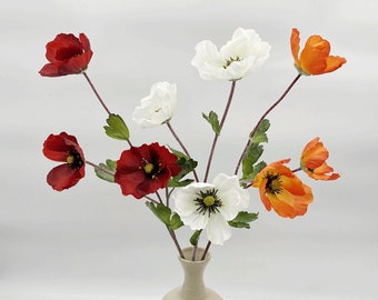 May include: A bouquet of artificial poppy flowers in a vase. The flowers are in shades of red, white, and orange.