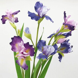 May include: A bouquet of artificial iris flowers in shades of purple, blue, and pink. The flowers have green stems and leaves.