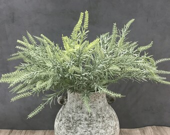 May include: A bouquet of artificial green and white lavender sprigs in a gray stone vase.