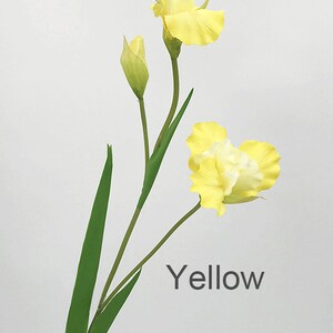 May include: A single stem of yellow artificial iris flowers with green leaves. The flowers have a white center and are in bloom. The text "Yellow" is printed below the flowers.