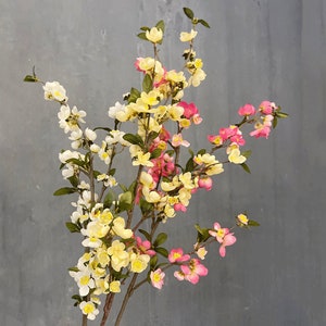 May include: A bouquet of artificial flowers with pink, yellow, and white blossoms. The flowers are arranged on a branch-like stem.