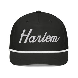 May include: Black baseball cap with a white rope trim and white embroidered text that says "Harlem" in a cursive font.