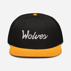 May include: A black and gold baseball cap with the word "Wolves" embroidered in white on the front.