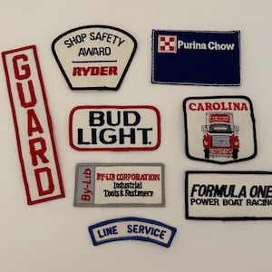 May include: A collection of nine embroidered patches featuring various logos and slogans. The patches are in different colors and shapes, including red, white, blue, and black. Some of the logos include "Bud Light", "Purina Chow", "Carolina", "Formula One", "Shop Safety Award Ryder", and "Line Service".