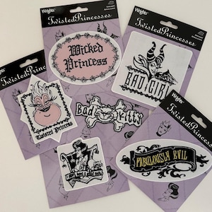 May include: A collection of "Twisted Princesses" iron-on patches. The patches feature various villainous characters with phrases like "Wicked Princess", "Bad Girl", and "Fabulously Evil". The patches are on purple backing cards.
