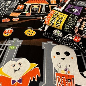 May include: Black fabric with a Halloween theme.  The fabric features a haunted house, a ghost, a vampire, a spider, pumpkins, and the text "Way to the Haunted House?" and "Spooky!"