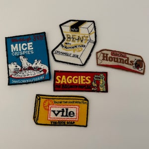 May include: Five embroidered patches with various designs and text. The patches are on a white background. The patches include a blue patch with the text "MICE CRISPIES", a red patch with the text "SAGGIES", a yellow patch with the text "vile", a brown patch with the text "Hounds", and a white patch with the text "BENT".