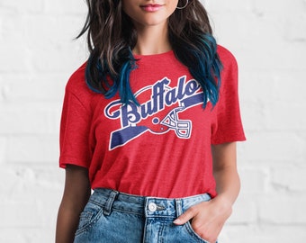 May include: Red t-shirt with a blue and white graphic of a football helmet and the word "Buffalo" in a vintage style font.