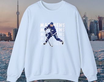 May include: Light blue sweatshirt with a hockey player graphic and the text "MATHEWS" repeated four times.