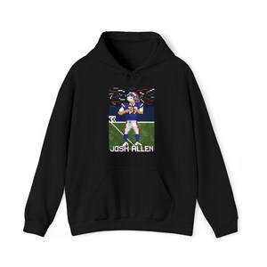 K&ouml;nnte beinhalten: Schwarzer Hoodie mit einem Pixelbild eines Footballspielers in einem blau-roten Trikot, unter dem Bild steht der Text "JOSH ALLEN".