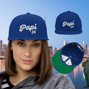 May include: A blue baseball cap with white embroidered cursive text that says "Papi 34".
