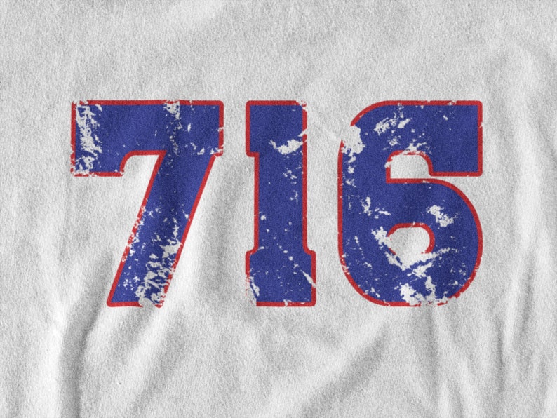 May include: A white t-shirt with a blue and red distressed number "716" printed on the front.