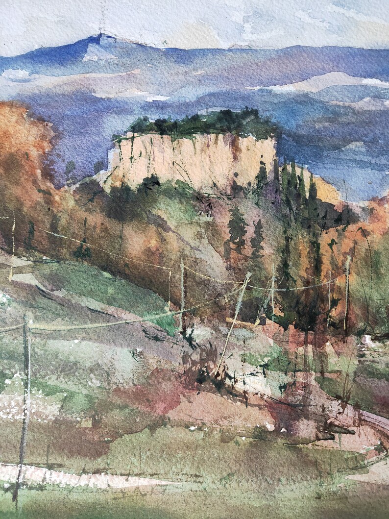 K&ouml;nnte beinhalten: Ein Aquarellbild einer Landschaft mit einer Klippe im Vordergrund und einem Gebirge im Hintergrund. Die Klippe ist hellbraun und hat ein paar B&auml;ume, die darauf wachsen. Das Gebirge ist hellblau und von einem leichten Nebel bedeckt. Das Bild ist in einem realistischen Stil gemalt.