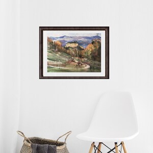 K&ouml;nnte beinhalten: Ein Aquarellbild einer Landschaft mit einer kurvigen Stra&szlig;e, die zu einem Bergdorf f&uuml;hrt. Das Bild ist in einem dunkelbraunen Rahmen gerahmt.