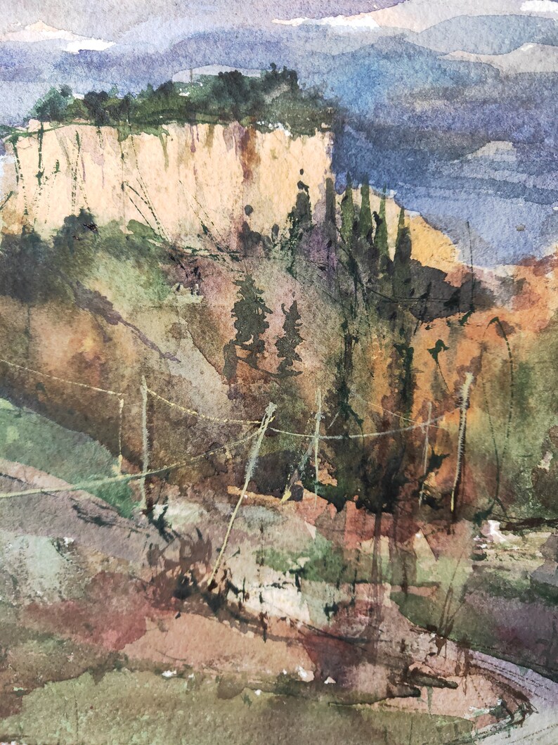 K&ouml;nnte beinhalten: Aquarellmalerei einer Klippenlandschaft mit einer felsigen Klippe, gr&uuml;nen B&auml;umen und einer blauen Bergkette in der Ferne.