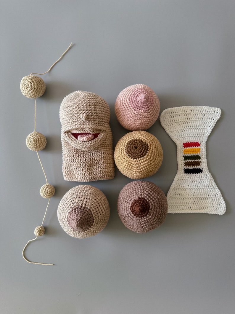 May include: A set of crocheted toys, including a brown puppet with a smiling face, a pink crocheted ball, a brown crocheted ball with a brown center, a white crocheted ball with a rainbow stripe, and two brown crocheted balls with brown centers.