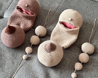 Op de afbeelding: Gehaakte borstvormen en tepelhoezen in beige en bruine tinten. De set bevat twee borstvormen, twee tepelhoezen en twee gehaakte zakjes met roze binnenkant. Extra kleine gehaakte ballen zijn aan draden bevestigd.