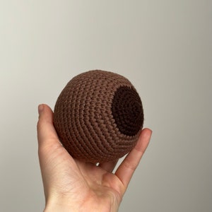 以下が含まれることがあります： 片側に濃い茶色のパッチが付いた、茶色の編み球