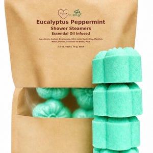 May include: A brown paper pouch containing mint green, flower-shaped shower steamers. The label reads Eucalyptus Peppermint Shower Steamers Essential Oil Infused, listing ingredients and a weight of 2.5 oz. each.