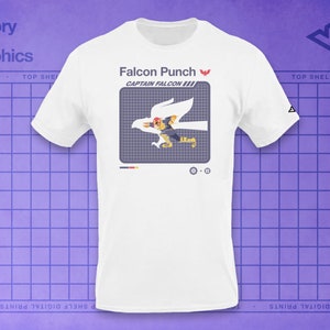 May include: White t-shirt with a graphic of Captain Falcon performing the Falcon Punch attack from the Super Smash Bros. video game series. The text "Falcon Punch" and "Captain Falcon" are printed on the shirt.