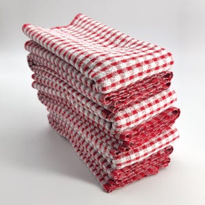 May include: A stack of red and white checkered kitchen towels. The towels are folded and neatly stacked, showcasing a classic gingham pattern. The bright red and white colors create a clean and inviting look, perfect for any kitchen.