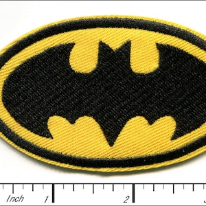 May include: Yellow and black embroidered iron-on patch of the Batman logo. The logo is a stylized bat silhouette inside an oval.