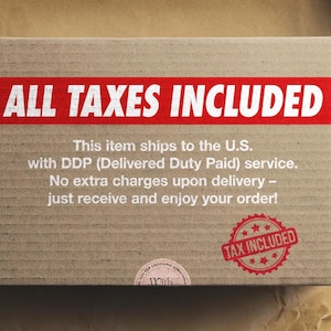 May include: A brown cardboard box with the words "ALL TAXES INCLUDED" in white on a red banner. A red stamp with the text "TAX INCLUDED" is also visible. The box is on a brown surface.