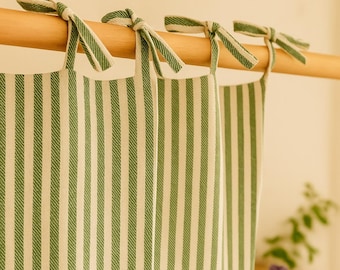 May include: Green and white striped curtains hanging from a wooden rod. The curtains are made of a textured fabric and are tied with matching green and white striped bows. The overall theme is home decor.