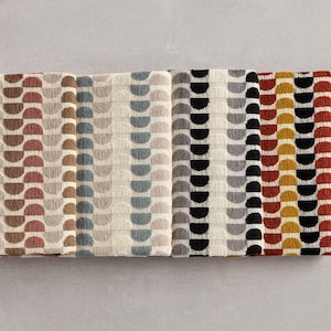 May include: Folded towels with a repeating semi-circle pattern in various colours. The towels feature brown, beige, grey, black, red, and yellow. The design is geometric and modern, suitable for a bathroom.