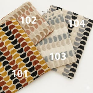 May include: A selection of patterned fabric swatches in different colours. The swatches are labelled 101, 102, 103, and 104. The patterns feature semi-circles and rounded shapes in yellow, brown, black, beige, and grey.