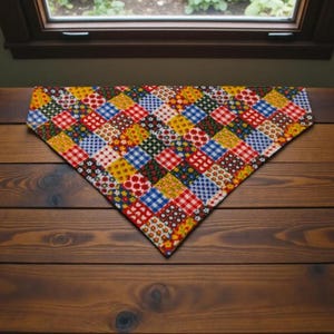 May include: A colorful patchwork bandana with a variety of patterns, including gingham, floral, and polka dots. The bandana is made of fabric and is displayed on a wooden surface. The color palette includes red, blue, yellow, and green.