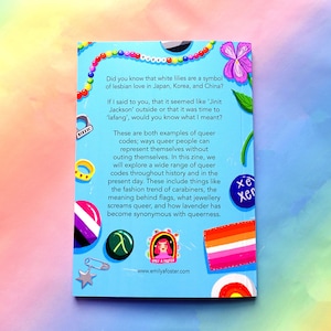 K&ouml;nnte beinhalten: Ein Buchcover mit blauem Hintergrund und bunten Illustrationen verschiedener queerer Symbole, darunter Flaggen, Blumen und Schmuck. Der Text auf dem Cover lautet "Wusstest du, dass wei&szlig;e Lilien ein Symbol f&uuml;r lesbische Liebe in Japan, Korea und China sind?" und "Dies sind zwei Beispiele f&uuml;r queere Codes; M&ouml;glichkeiten f&uuml;r queere Menschen, sich zu repr&auml;sentieren, ohne sich zu outen. In diesem Zine werden wir eine gro&szlig;e Bandbreite an queeren Codes im Laufe der Geschichte und in der Gegenwart erforschen."