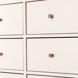 May include: White chest of drawers with six drawers and wooden square knobs.