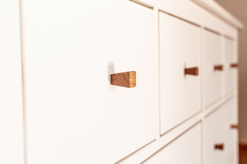 May include: White chest of drawers with six drawers and wooden knobs. The drawers have a subtle lip around the edges.