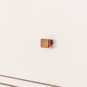 May include: A white drawer with a square wooden knob.