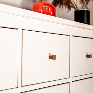 May include: White dresser with six drawers and wooden knobs. The drawers are closed and the dresser is empty.