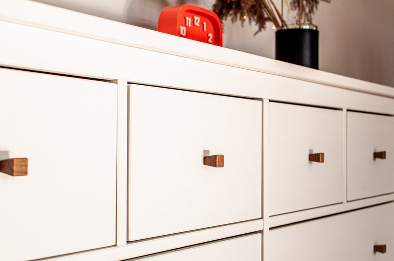 May include: White dresser with six drawers and wooden knobs. The drawers are closed and the dresser is empty.