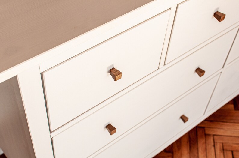May include: White dresser with six drawers and wooden knobs. The dresser has a light wood finish and is made of solid wood.