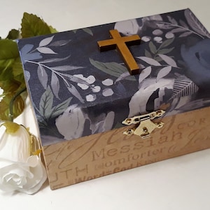 May include: A small wooden box with a floral design and a gold cross on the lid. The box has a latch and is decorated with the words "Truth Messiah Comforter" on the bottom.