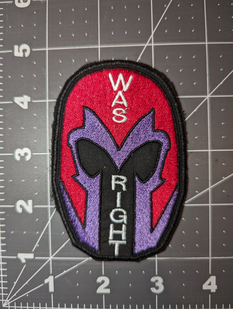 Peut inclure: Un patch brod&eacute; repr&eacute;sentant une silhouette violette et noire du casque de Magneto avec les mots "WAS RIGHT" en texte blanc.