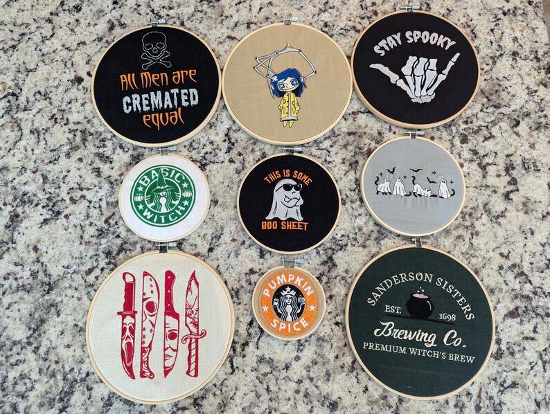 May include: A collection of embroidered hoops with Halloween and witch-themed designs. The hoops feature phrases like "Stay Spooky" and "Sanderson Sisters Brewing Co." along with spooky graphics and a Starbucks-inspired design.